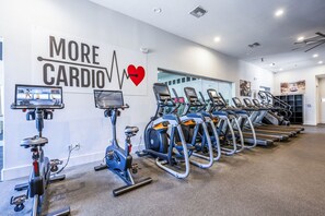 Un gimnasio con equipo cardiovascular, una pared que dice 'MORE CARDIO' y un símbolo de corazón, y una cinta de correr en el centro.