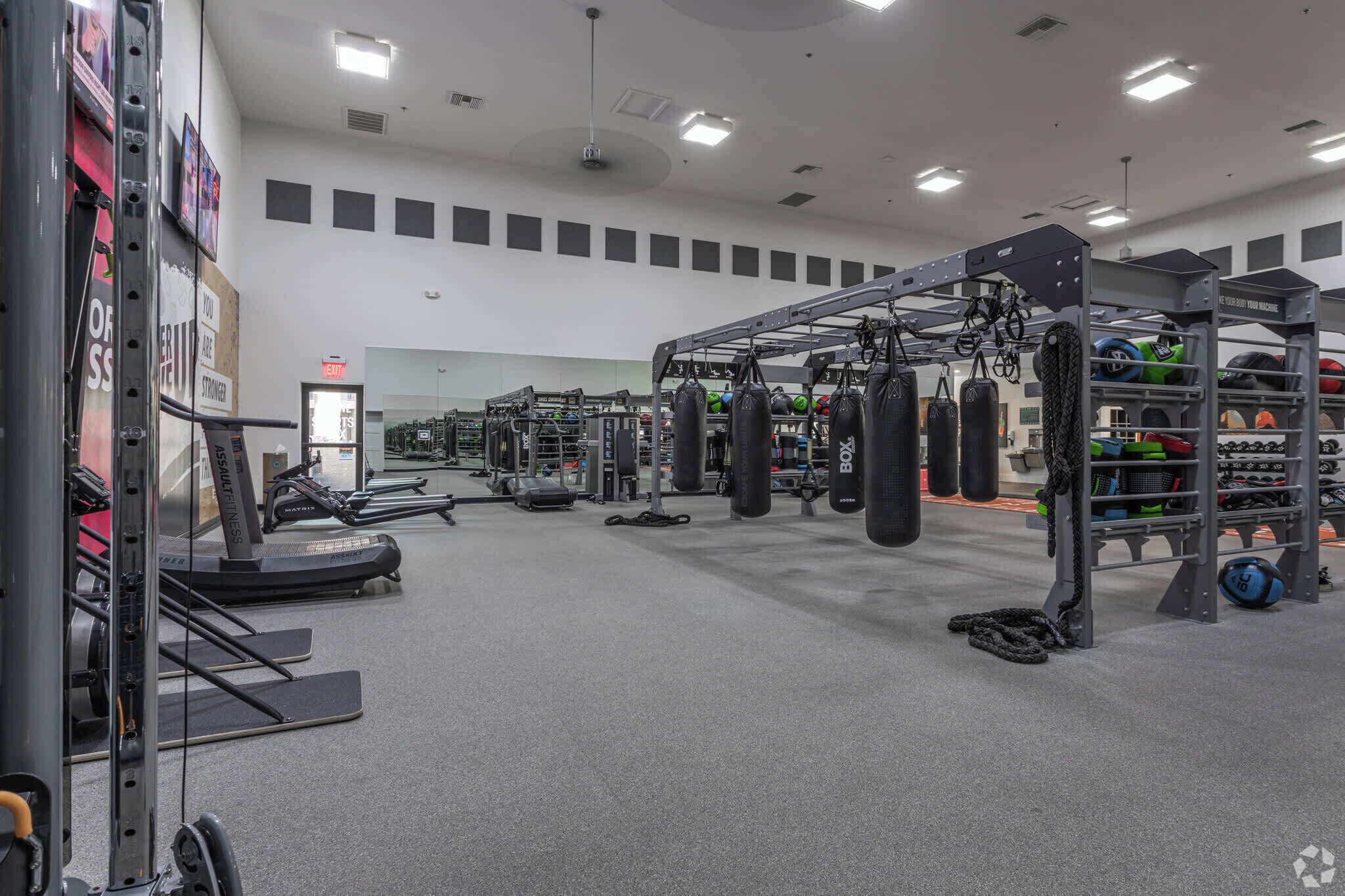 A gym with treadmills, weight machines, punching bags, and a variety of fitness equipment.