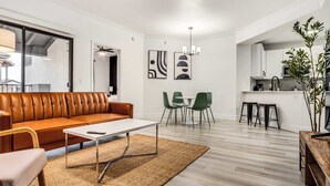 A modern living room with a leather sofa, a coffee table, and a dining area with chairs.