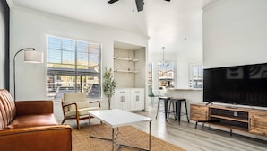 A modern living room with a sofa, coffee table, TV, and kitchen area.
