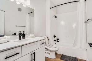 Een moderne badkamer met een wit wastafelmeubel, toilet en bad.
