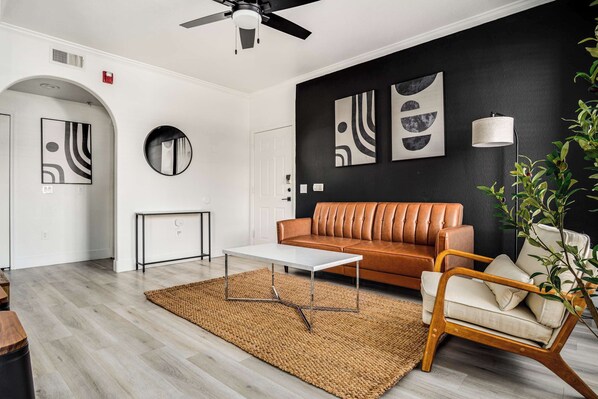 Een moderne woonkamer met een bank, salontafel en een ronde spiegel.