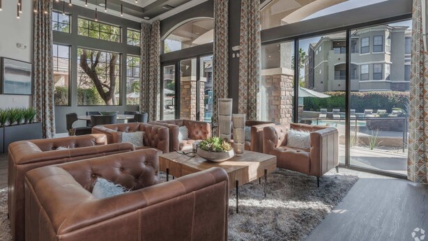 A spacious indoor area with leather sofas, a coffee table, and large windows offering views of a residential area. - Boulevard Stays 2BR by Stadium Pool, Parking, Gym 10 (Glendale)