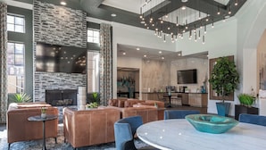 A spacious living area with a stone fireplace, leather sofas, a dining table, and a kitchen in the background. - Boulevard Stays 2BR by Stadium Pool, Parking, Gym 10 (Glendale)