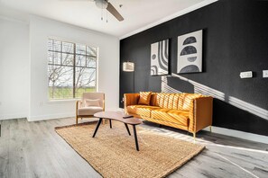 A modern living room with a sofa, a chair, a coffee table, and artwork on the wall. - Boulevard Stays 1BR by the Stadium Pool, Parking, Gym 11 (Glendale)