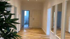 Un couloir doté d’un plancher en bois, de murs blancs et d’une porte au fond.