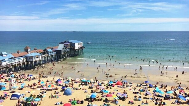 A beach with a pier and beachgoers.