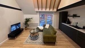 Un salon moderne avec un canapé vert, un téléviseur, une table basse et une plante.
