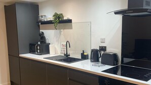 Une cuisine moderne dotée d’un plan de travail noir, d’une cuisinière encastrée, d’un évier et d’une machine à café.
