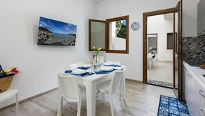 Un coin repas avec une table dressée pour deux personnes, un tableau accroché au mur et un miroir qui reflète la pièce.