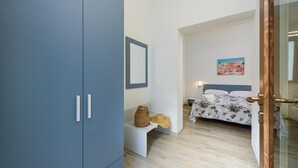 Une chambre à coucher avec un lit, un banc, une armoire et un tableau au mur.