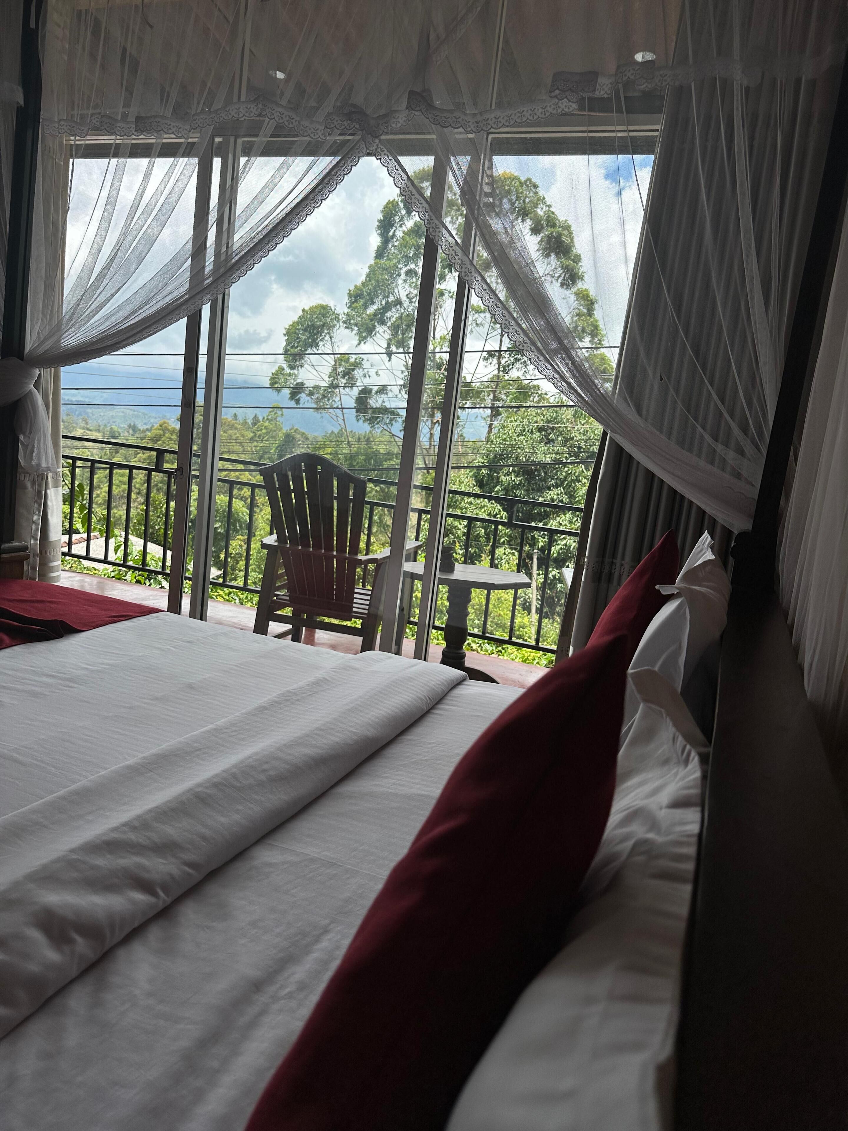 Ein Schlafzimmer mit einem großen Bett, einem Sessel und einem Balkon mit Landschaftsblick.
