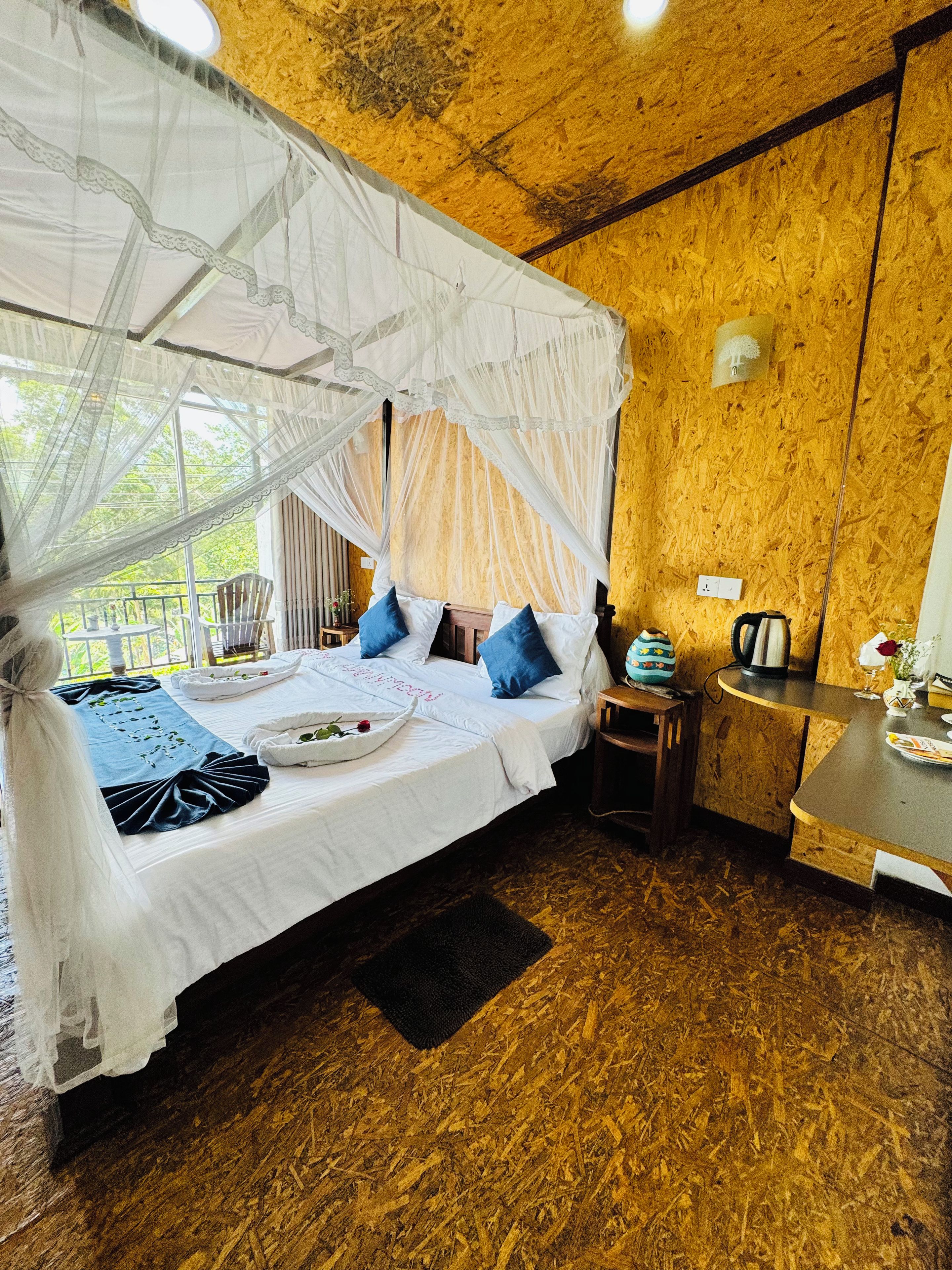 A room with a bed, a small table, and a window with a view.