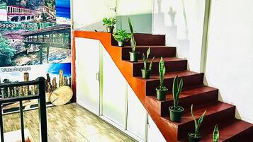 A staircase with potted plants, a poster of a cityscape, and a wooden floor.