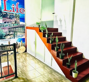 A staircase with potted plants, a poster of a cityscape, and a wooden floor.