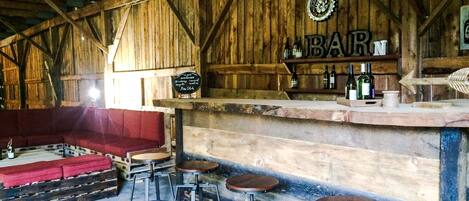 A rustic wooden interior with a bar area, wooden beams, and a red cushioned seating area.