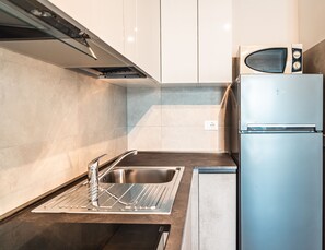 A modern kitchen with a stainless steel sink, a built-in microwave, and a refrigerator. - Bright Apartment Near the Beach in Bibione (San Michele al Tagliamento)
