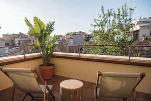 A balcony with two chairs, a small round table, and a potted plant.