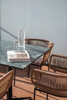 A round table with a clear glass pitcher and a book, surrounded by wicker chairs.