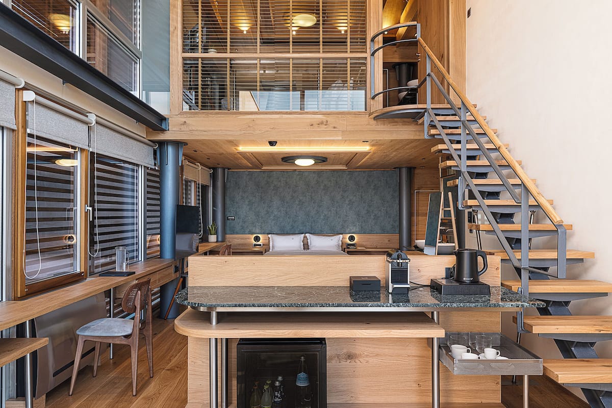Een moderne keuken met een centraal eiland, houten vloeren en een trap naar een hoger niveau.