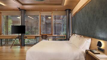 A modern bedroom with a large bed, a desk, a chair, and a TV.