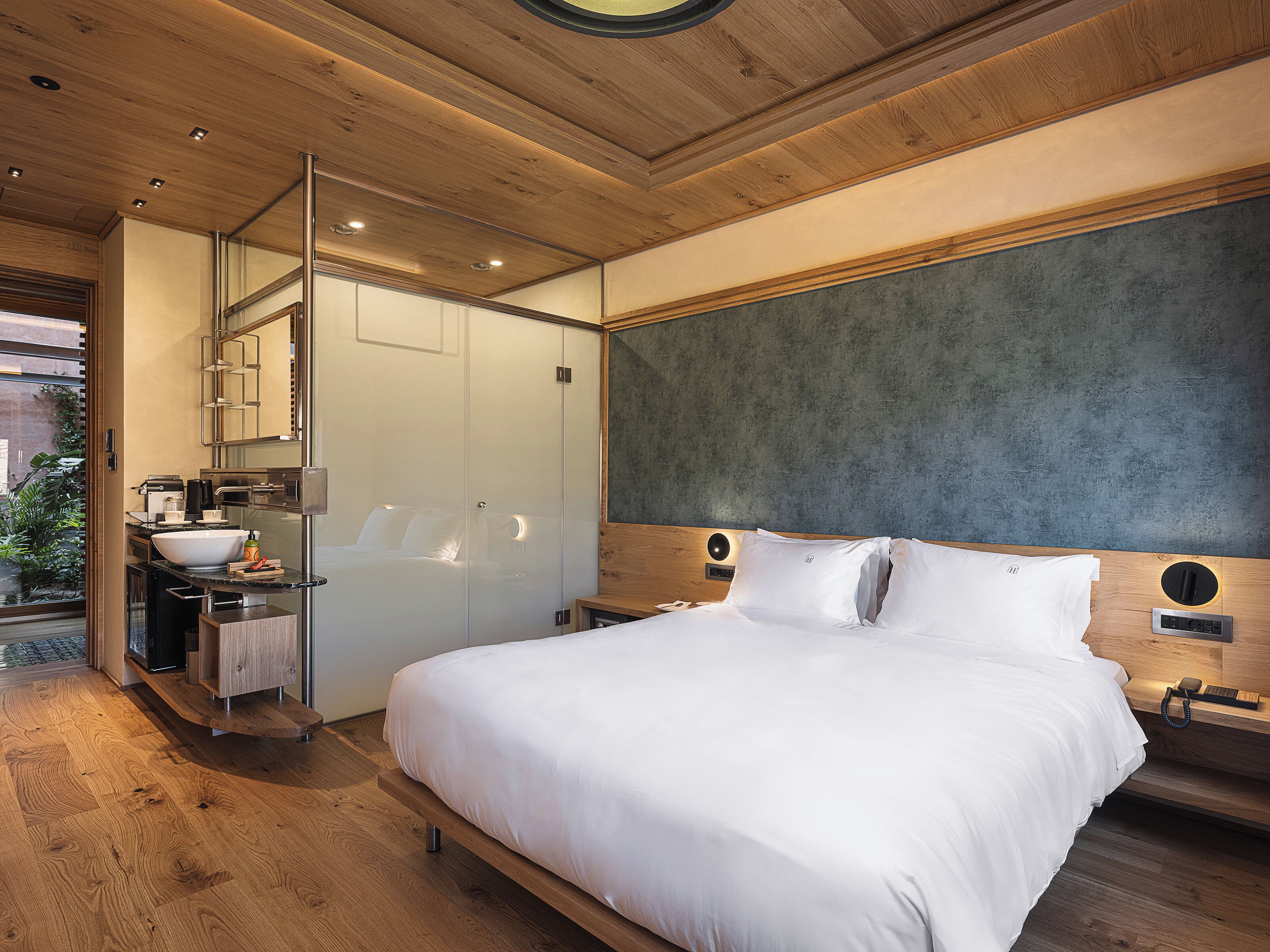 A modern bedroom with a large bed, a built-in wardrobe, and a bathroom with a glass partition.