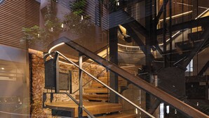 A modern staircase with glass railings and wooden steps, surrounded by stone walls and indoor plants. - Elysia Boutique Hotel (Chania)