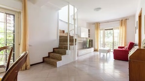 A spacious living area with a staircase, a dining area, and a red sofa.