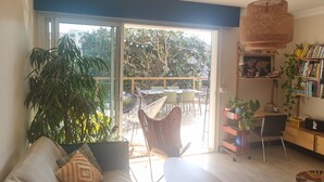 A living room with a sofa, a large potted plant, a dining area with chairs and a table, and a bookshelf. - Well-decorated family home, 2 steps from the bike path. (Agde)