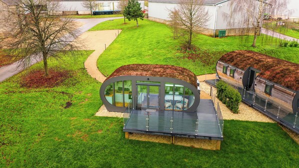 Une maison moderne dotée d’une façade circulaire en verre originale, d’une petite terrasse et d’un toit végétalisé.