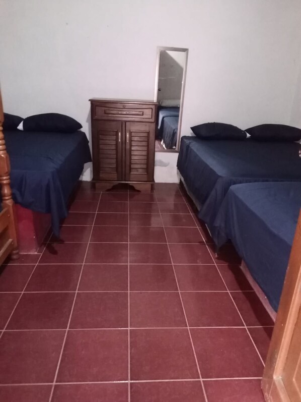 Une chambre avec deux lits, une armoire en bois et un miroir au mur.