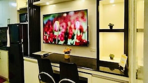 Een kleine keuken met een eethoek, een flatscreen televisie en een kleine potplant.