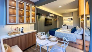 Une chambre d’hôtel compacte comprenant un coin repas, une kitchenette et un lit.