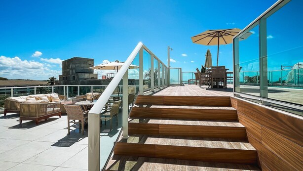 Une terrasse sur le toit avec des sièges extérieurs, un escalier et une vue sur l’océan.