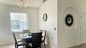 Ein Essbereich mit Tisch für vier Personen, einer Kandelaber, einer Uhr und einem dekorativen Spiegel an der Wand.