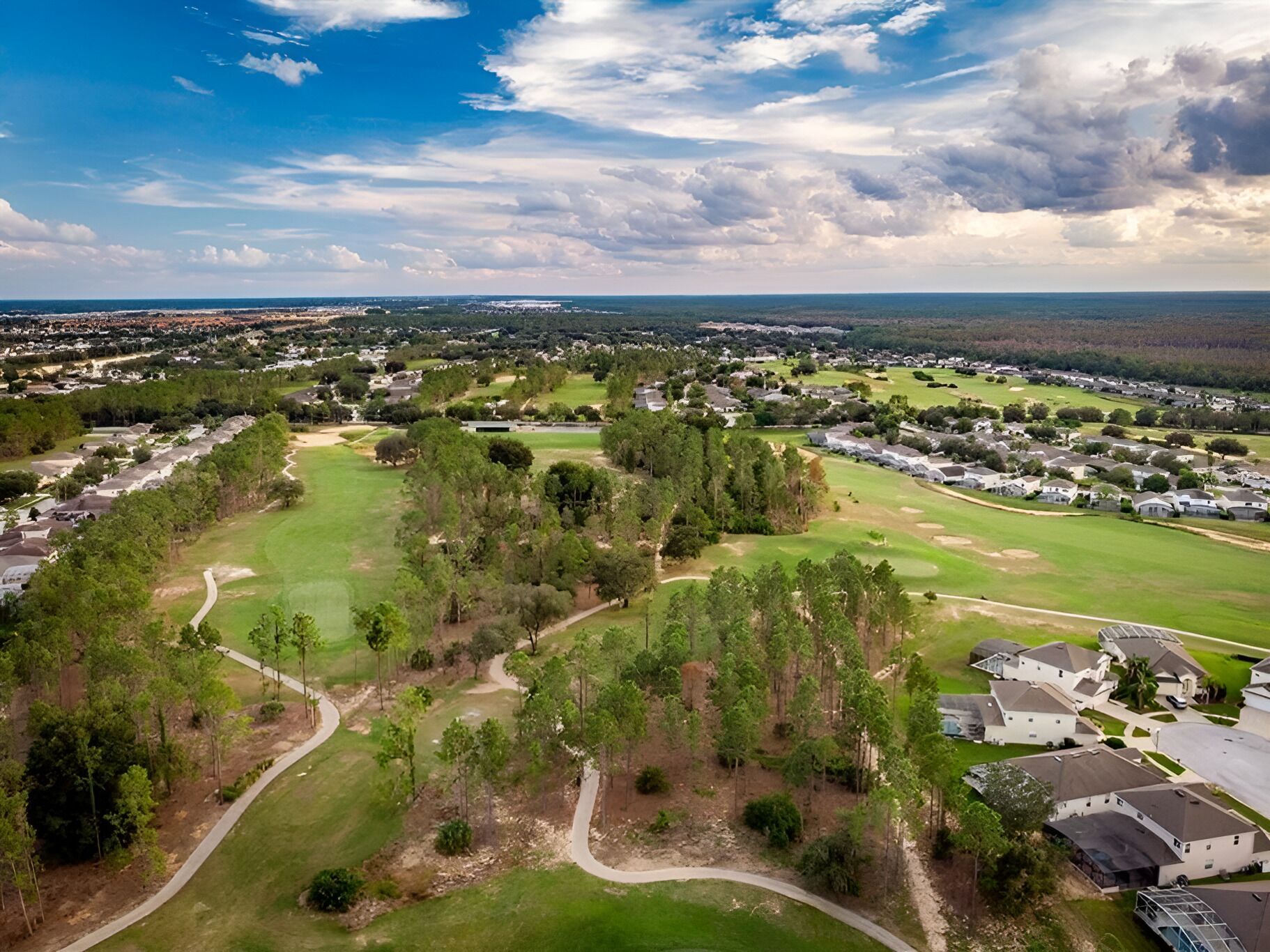 Vista aérea de un campo de golf con zonas residenciales y cielo despejado.