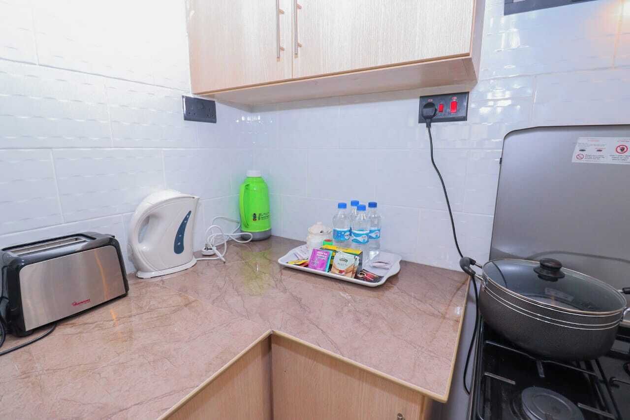 A compact kitchen with a toaster, kettle, green bottle, and water bottles on the counter.