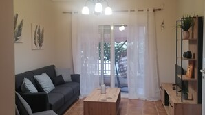 Una sala de estar con un sofá gris oscuro, una mesa de centro de madera y una lámpara de techo.