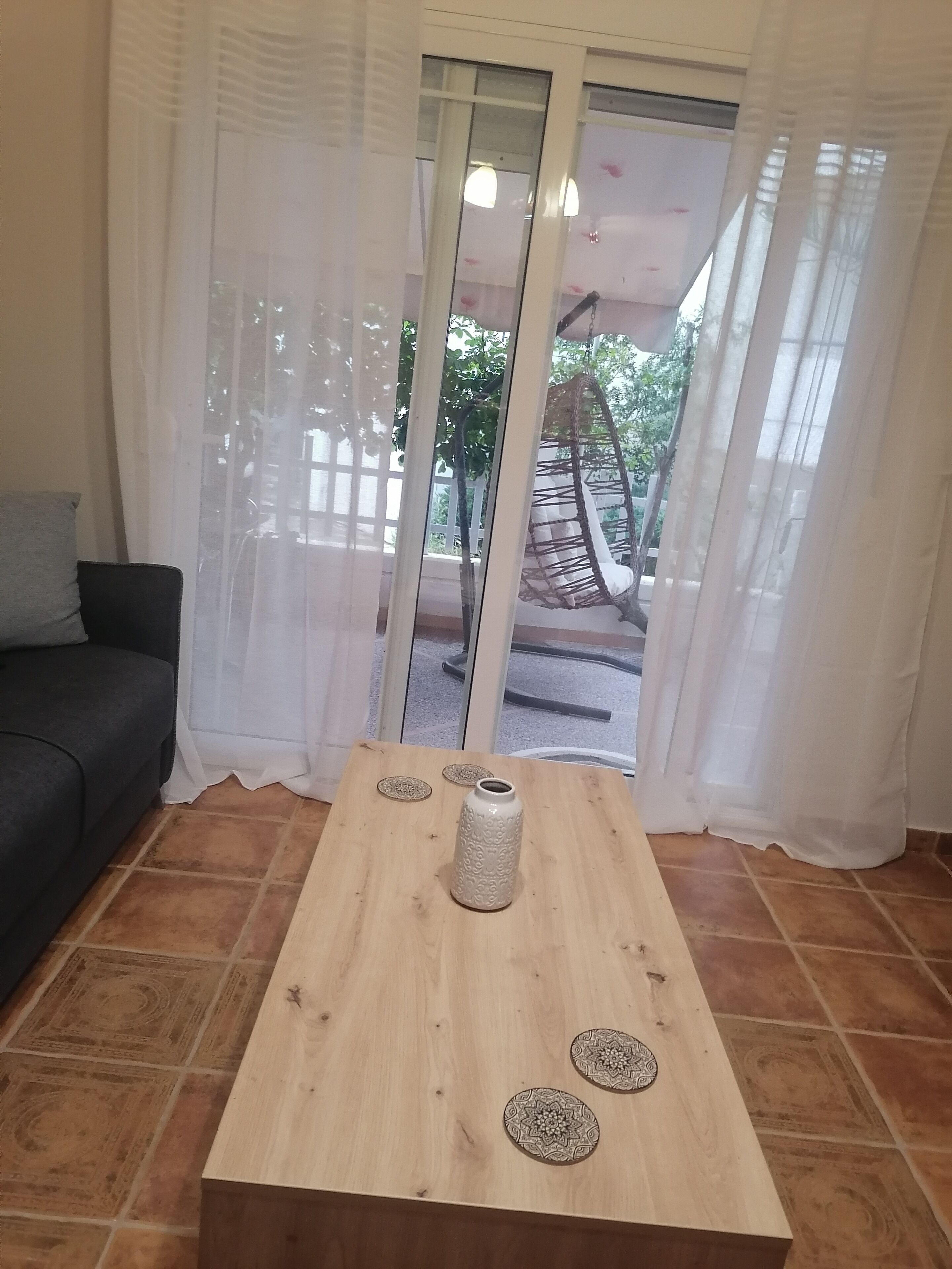 A living room with a wooden coffee table, a white vase, and two decorative plates.