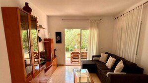 A living room with a sofa, a glass coffee table, a wooden cabinet, and a large mirror. - Villa Rosell (L'Escala)