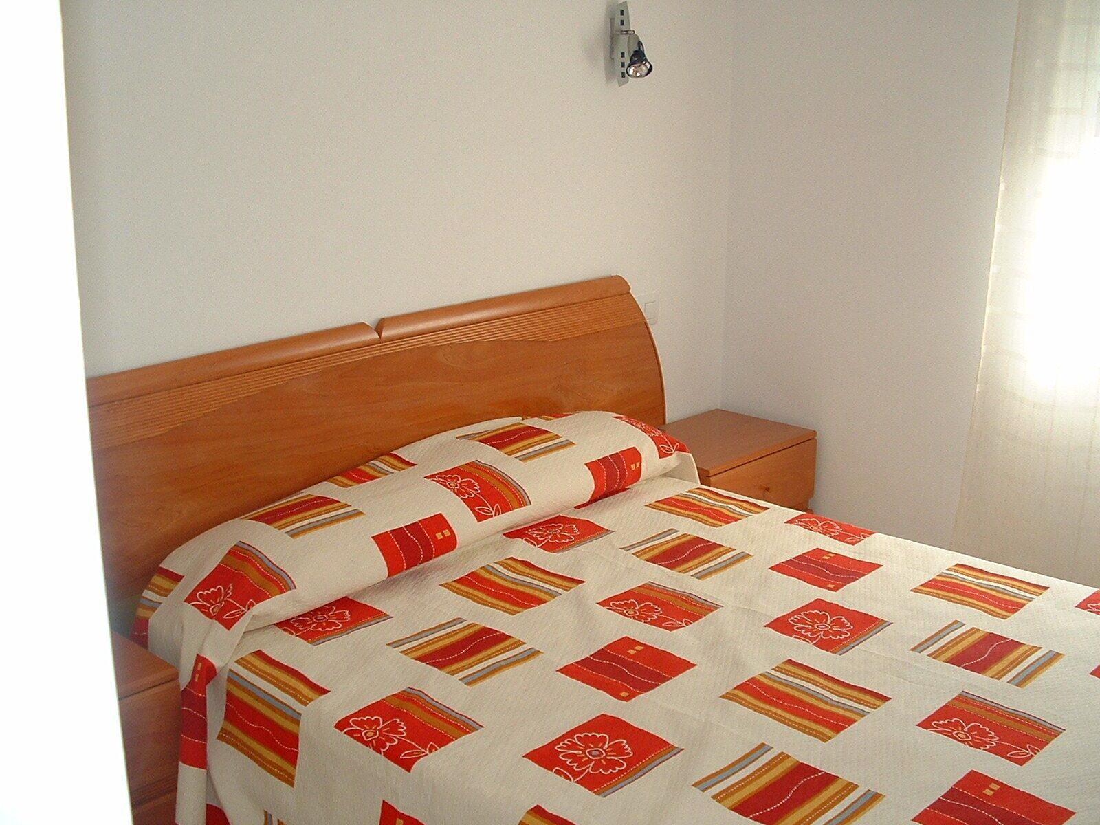 Un lit avec une couvre-lit à motifs et une tête de lit en bois.