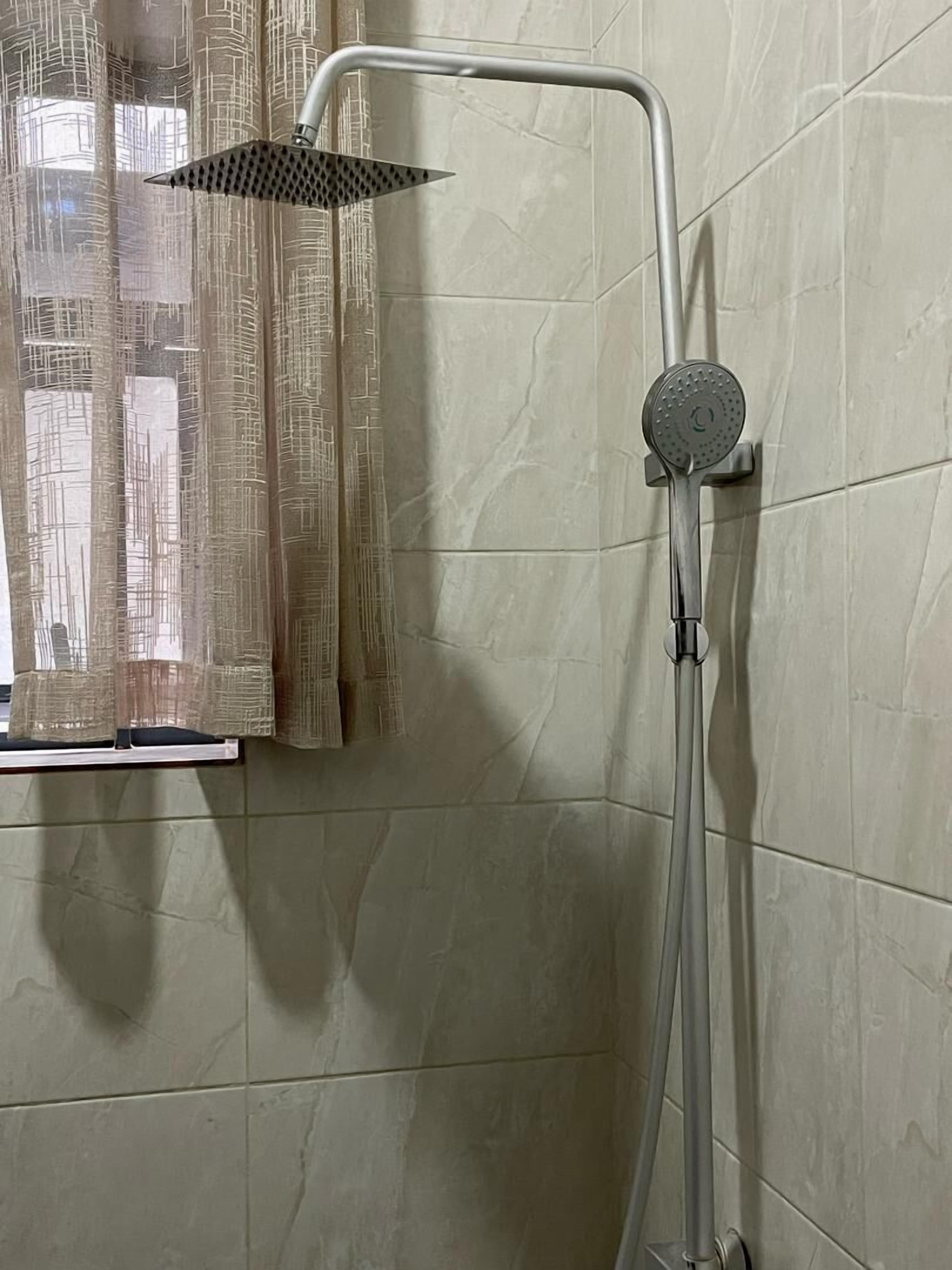 A shower with a handheld showerhead and a wall-mounted control.