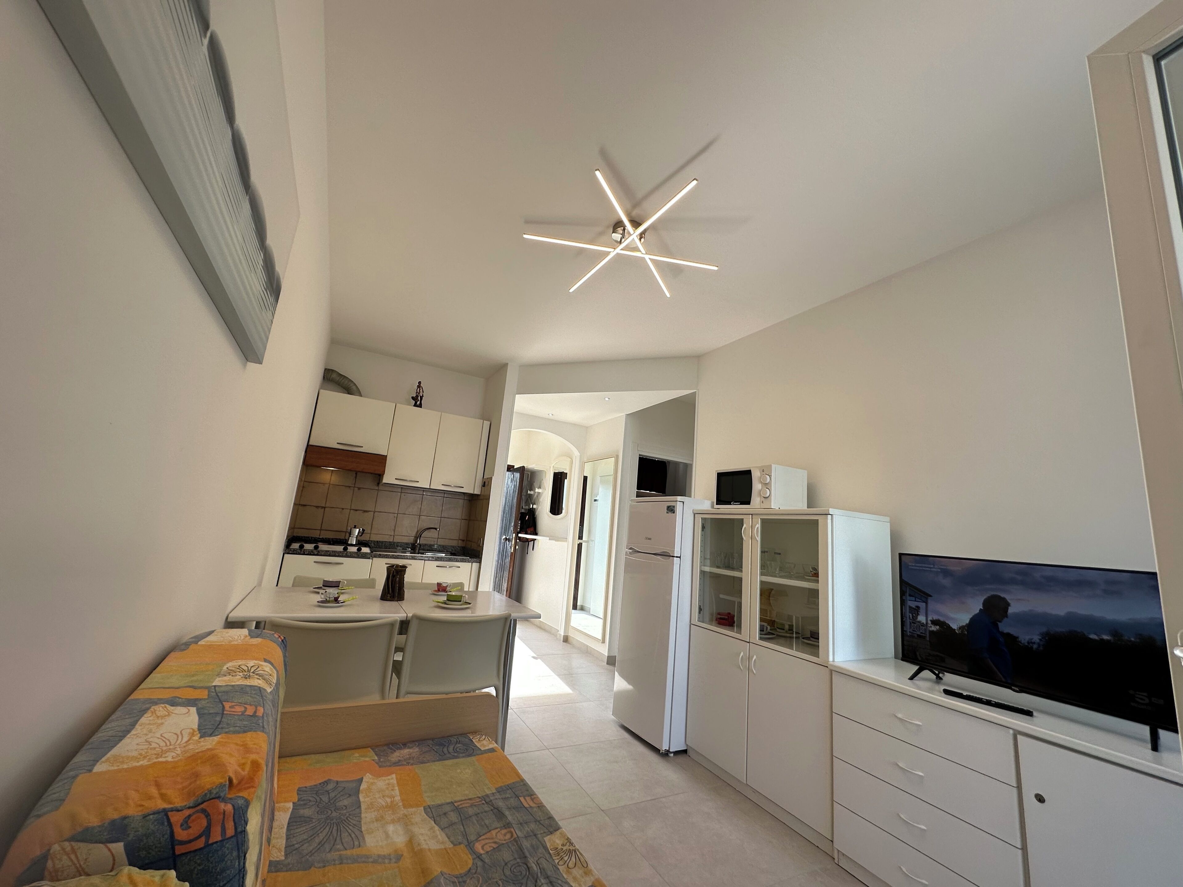 Un espacio habitable compacto con kitchenette, comedor y televisor.