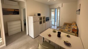 Une cuisine compacte équipée d’un réfrigérateur, d’un four à micro-ondes et d’une table à manger pour deux personnes, avec assiettes et tasses.