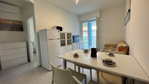 Une cuisine moderne avec un réfrigérateur blanc, un four à micro-ondes et une table à manger avec des chaises.