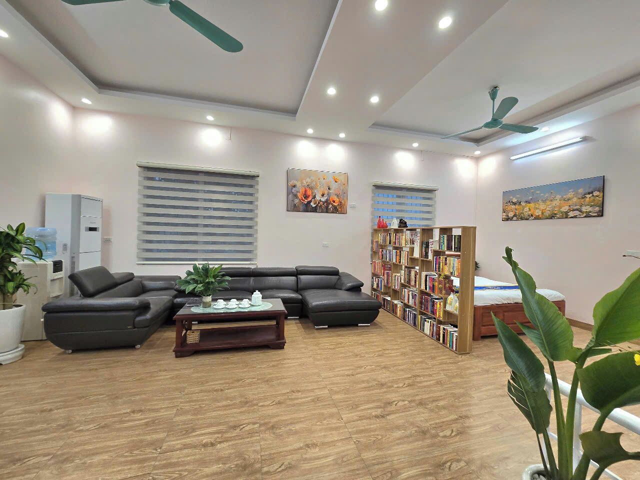 A modern living room with a sectional sofa, a coffee table, a bookshelf, and a ceiling fan.