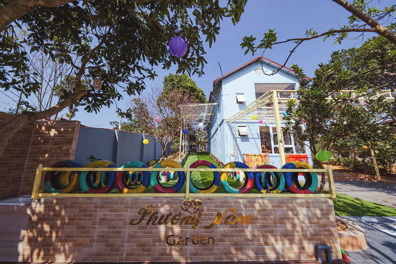 A brick wall with colorful tires and a sign reading "Phong Nam Garden."