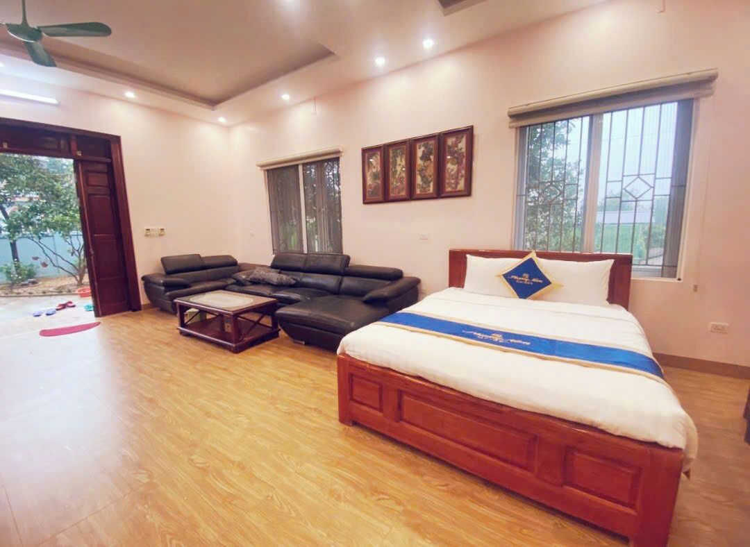 A bedroom with a bed, a sofa, a coffee table, and a ceiling fan.