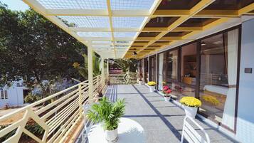 A covered outdoor area with a white railing, potted plants, and a seating area with a table and chairs.