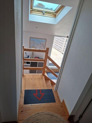 A narrow stairway leading to a loft bedroom with a skylight, wooden railings, and a view of the outside. - 6 min. drive from 'L'ESCAPADE' beaches Côte des Sables Enclosed garden 2 pl. park (Plounévez-Lochrist)